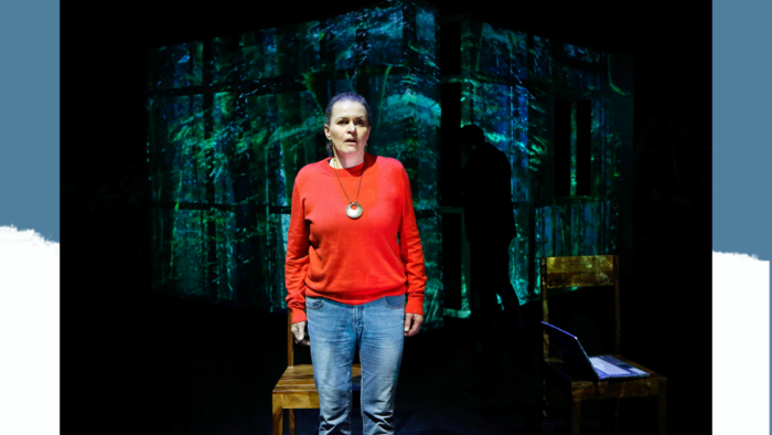 Schauspielerin steht auf einer Bühne, im Hintergrund Waldkulisse